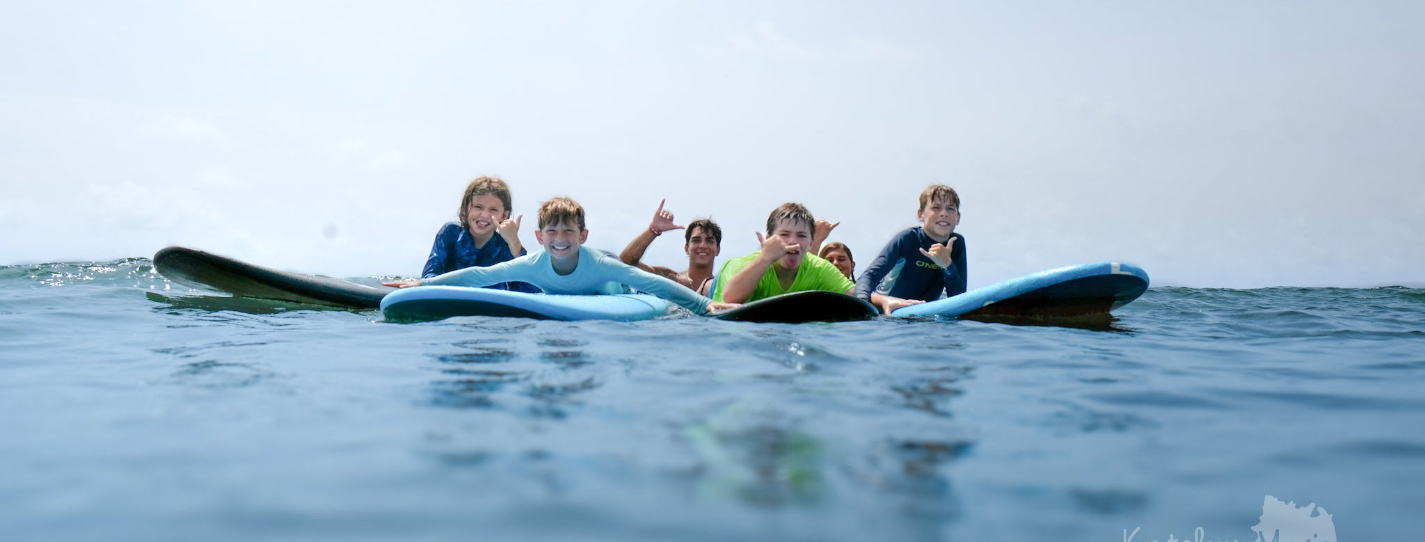 Four people on a surfboard in the ocean with a clear sky.